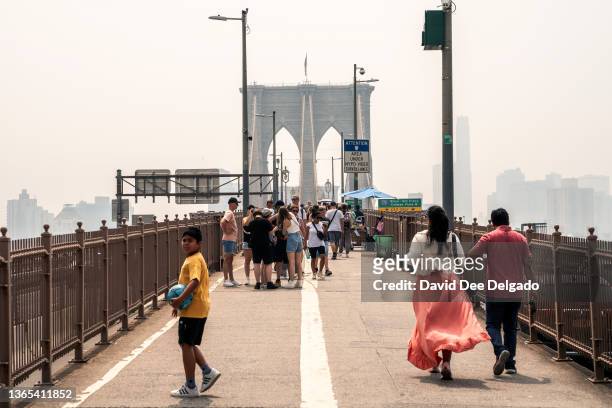 People walk over the Brooklyn Bridge as smoke from wildfires in Canada shrouds the area on June 30, 2023 in New York City. The eastern U.S. Is once...