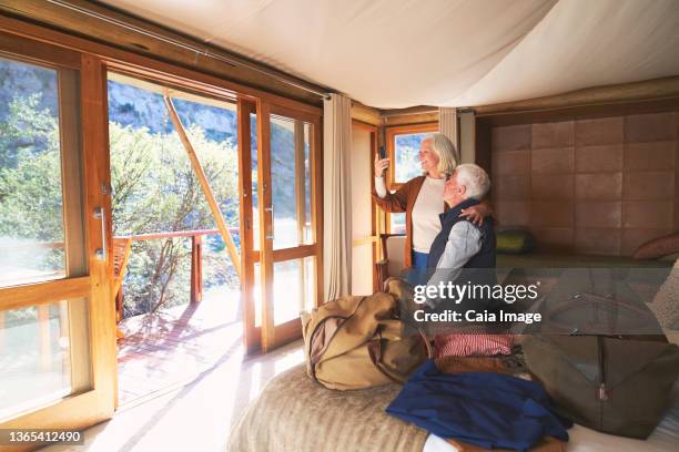senior couple using smart phone in safari hotel room - safari lodge stock pictures, royalty-free photos & images
