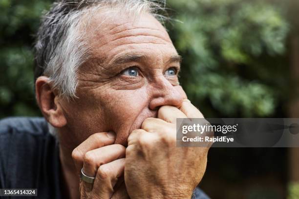 handsome man in his 50s deep in thought, looking apprehensive about the future - guy with face in hands stockfoto's en -beelden