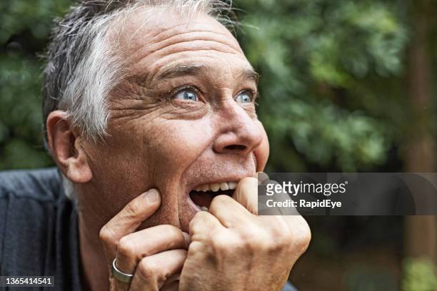 gutaussehender mann in seinen 50ern bekommt eine glückliche überraschung im freien in einem üppigen garten - mann verwirrt stock-fotos und bilder