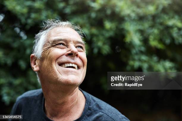 handsome man in his 50s looks up, smiling and joyful - satisfaction bildbanksfoton och bilder