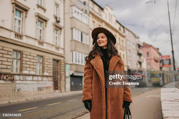 eine lächelnde junge frau in der innenstadt - street style winter stock-fotos und bilder