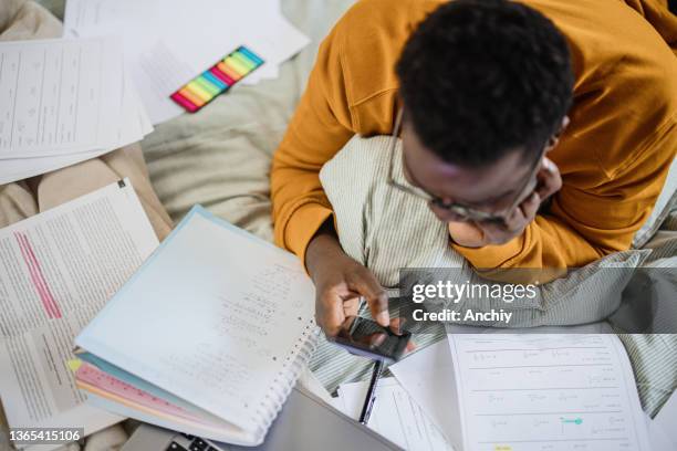 top view of a male student using smart phone while studying at home - working on laptop in train top view imagens e fotografias de stock