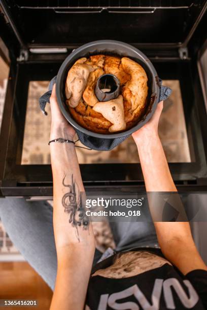 mujer joven sacando el pastel de vacaciones horneado del horno. - molde fotografías e imágenes de stock