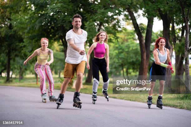 smiling group of people roller-skates together in the park - inline skating man park stock pictures, royalty-free photos & images