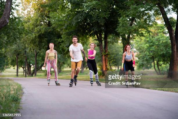 small group of women and man roller-skating in the park - inline skating man park stock pictures, royalty-free photos & images
