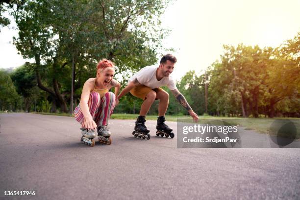 happy woman and man having fun on roller skates - skating park stock pictures, royalty-free photos & images