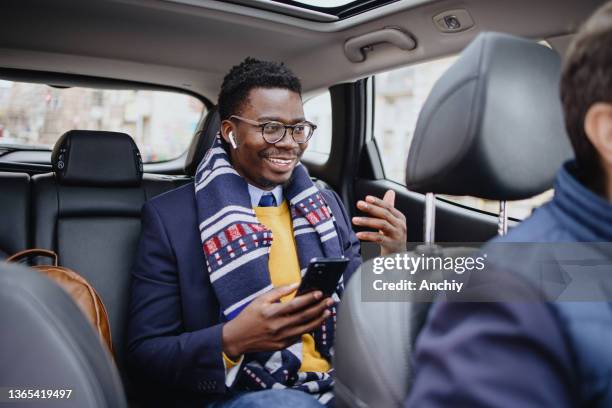 a man makes a business call while taking a taxi - driver passenger stock pictures, royalty-free photos & images