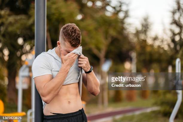 young man taking a break after training outdoors - athlete torso stock pictures, royalty-free photos & images