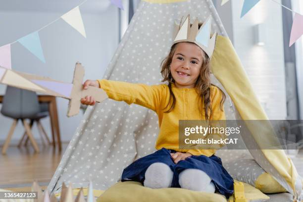 kostümiertejunges mädchen spielt vor einem zelt mit einer krone auf dem kopf - indoor kids play area stock-fotos und bilder