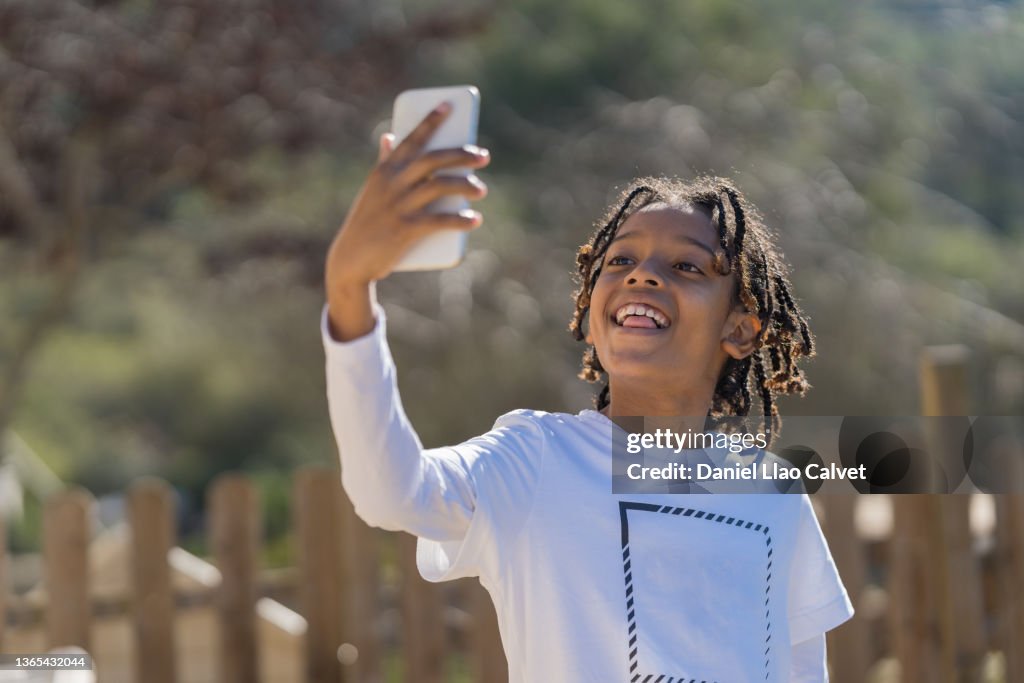 Boy in a white t-shirt takes a selfie with his mobile phone