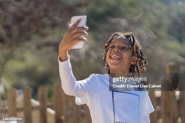 boy in a white t-shirt takes a selfie with his mobile phone - colombian ethnicity stockfoto's en -beelden