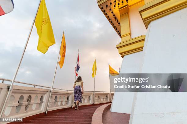 girl climbing the stairs to the top of wat saket temple (golden mount) in bangkok city, thailand. - buddhist flag stock pictures, royalty-free photos & images