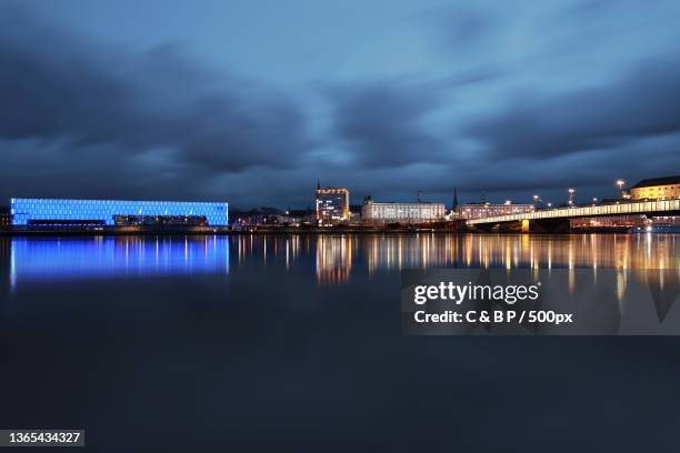 blue,scenic view of illuminated city by sea against sky at night,linz,austria - linz stock-fotos und bilder