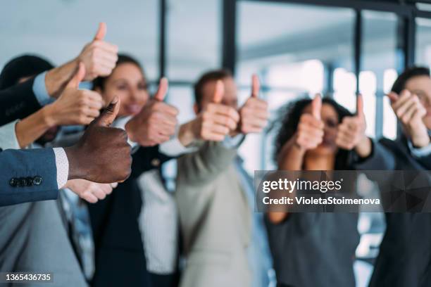 fröhliche geschäftsleute zeigen daumen hoch im büro. - thumbs up stock-fotos und bilder