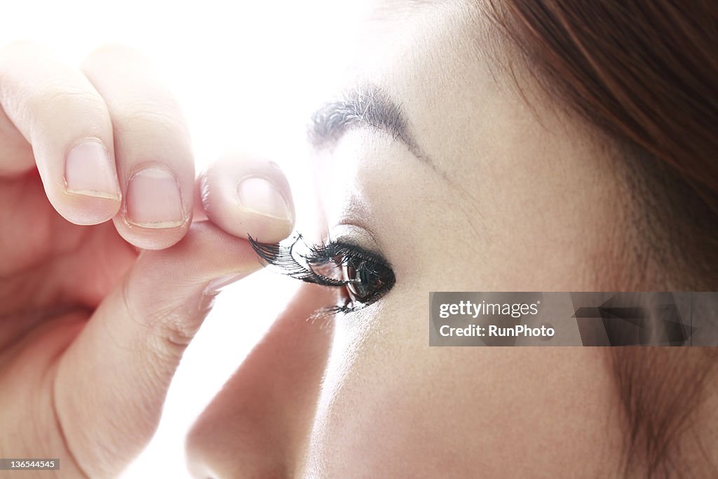 Young woman removing false eyelash