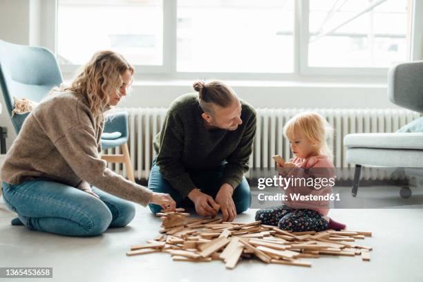 cute girl playing jenga with parents at home - jenga stockfoto's en -beelden