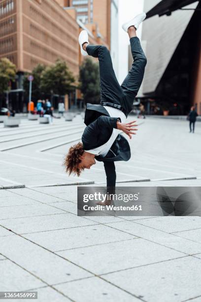 excited businessman doing handstand on square at potsdamer platz - hacer el pino fotografías e imágenes de stock