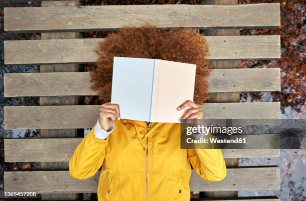 woman covering face with book lying on bridge in autumn forest - no face ストックフォトと画像