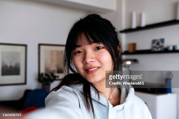 smiling woman with bangs taking selfie at home - bangs stock pictures, royalty-free photos & images