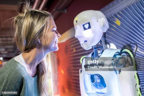 tech developer smiling in front of human robot at workshop - robotic heart stock-fotos und bilder