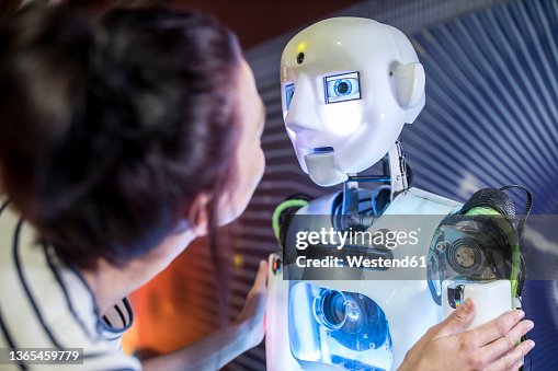 Tech developer looking at human robot in workshop Tech developer looking at human robot in workshop