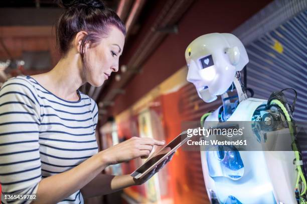 technician programming human robot through tablet pc at workshop - robot stock pictures, royalty-free photos & images