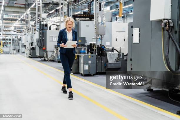 businesswoman using tablet pc walking at modern factory - tablet production stock-fotos und bilder