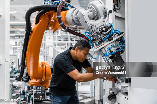 engineer examining robotic arm in factory - factory stock-fotos und bilder