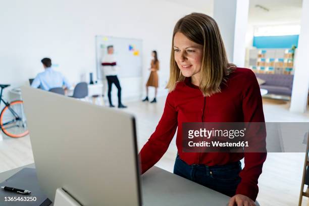 businesswoman with blond hair using desktop pc in office - small group of people foto e immagini stock