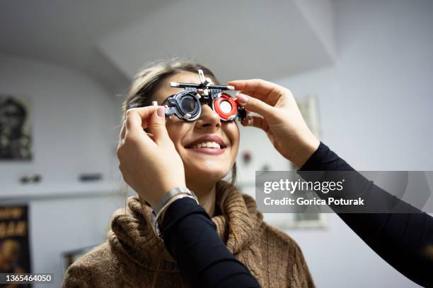 jeune femme subissant un examen de la vue avec un équipement de test de la vue - réfracteur photos et images de collection