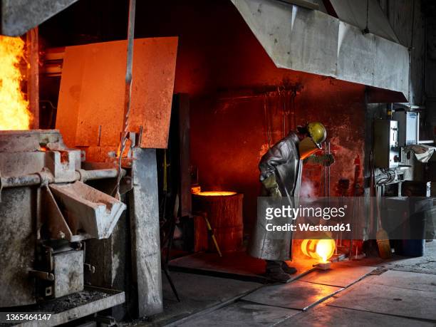 craftsperson pouring burning metal while working in industry - metallindustrie stock-fotos und bilder