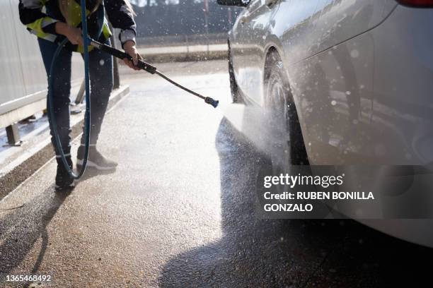 unrecognizable woman washing car at self-serve car wash with high pressure washer. - car splashing water on people stock pictures, royalty-free photos & images