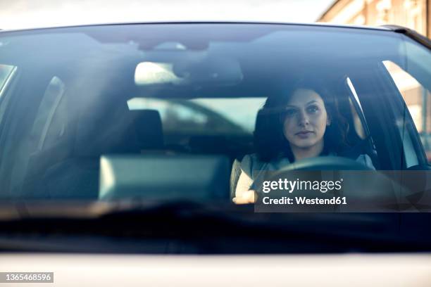 woman driving electric car seen through windshield - windshield stock pictures, royalty-free photos & images