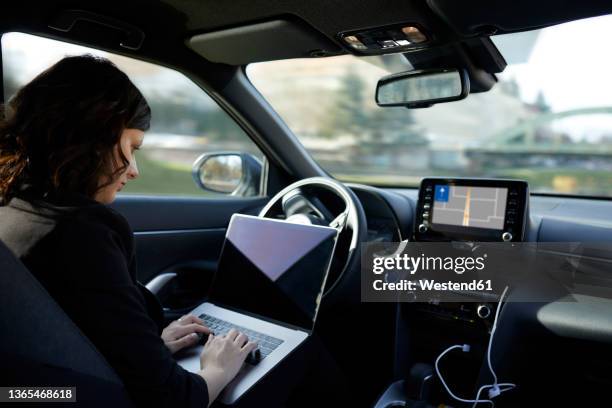 businesswoman with laptop working in driverless car - fahrerloses transportmittel stock-fotos und bilder