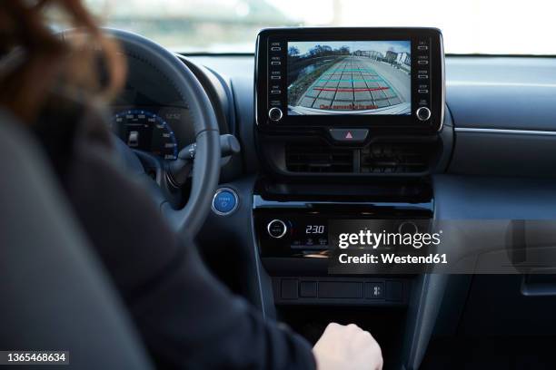 businesswoman parking car through digital display of backup camera - achteruitrijden stockfoto's en -beelden