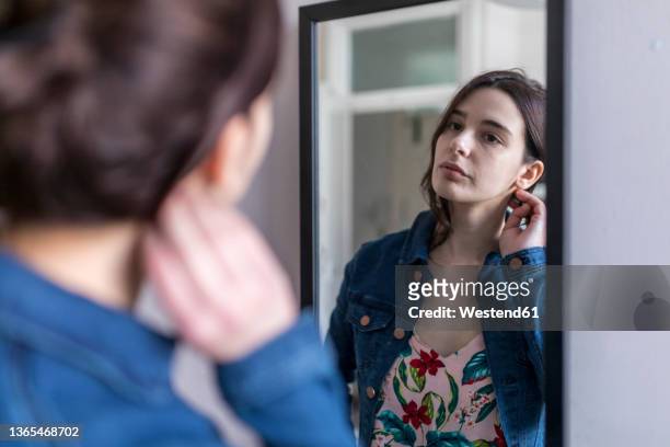 young woman looking in mirror at home - em frente de imagens e fotografias de stock