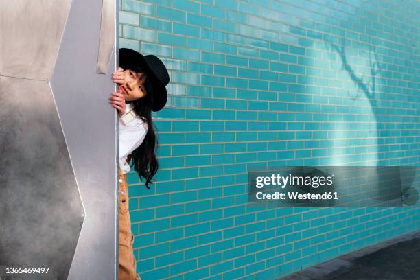 woman hiding and peeking out through door - hide stockfoto's en -beelden