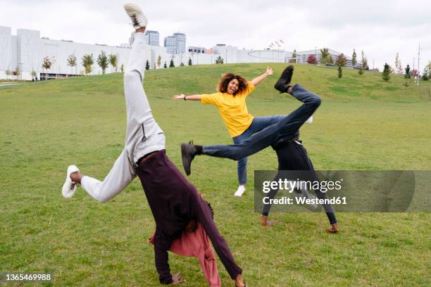 carefree young men doing cartwheel by friend in park - cartwheel stock pictures, royalty-free photos & images