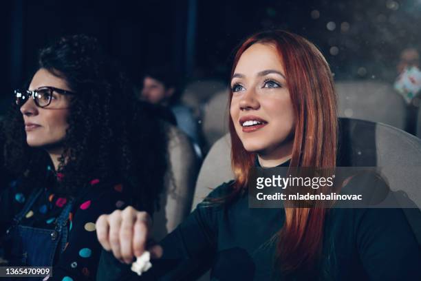 close up of a group of friends enjoying a movie in the cinema - girlfriends films stockfoto's en -beelden