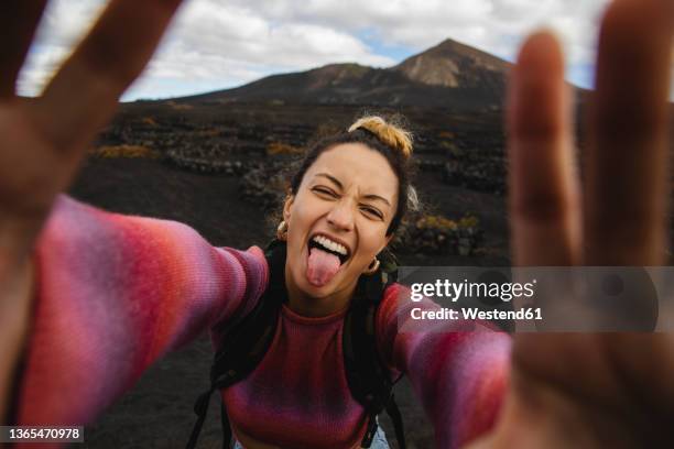 happy woman sticking out tongue and taking selfie with landscape in background - woman adventure stock pictures, royalty-free photos & images