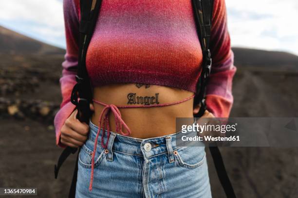 woman with angel word tattoo on stomach - crop top stock pictures, royalty-free photos & images
