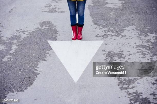 woman standing on arrow symbol on road - low section of woman standing in front of arrow sign on road stock pictures, royalty-free photos & images