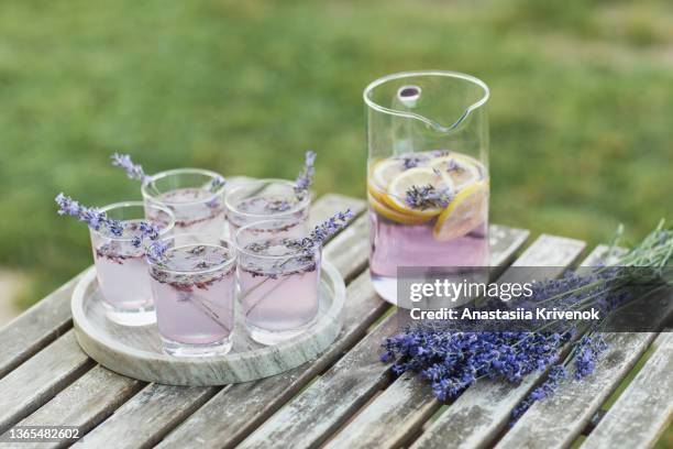 violet lavender cocktail decorated with flowers on wooden table outdoor. - zitronen feld stock-fotos und bilder