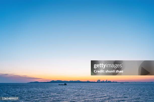 city silhouette seen from the sea at sunset - dusk gradient stock pictures, royalty-free photos & images