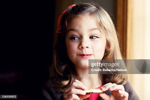 girl holding cookie with crumbs on her face - krümel stock-fotos und bilder