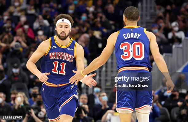 Klay Thompson high fives Stephen Curry of the Golden State Warriors as he runs back downcourt against the Detroit Pistons at Chase Center on January...
