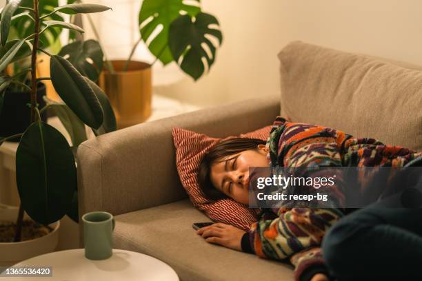 young woman relaxing on sofa at night - hot night sleep stock pictures, royalty-free photos & images
