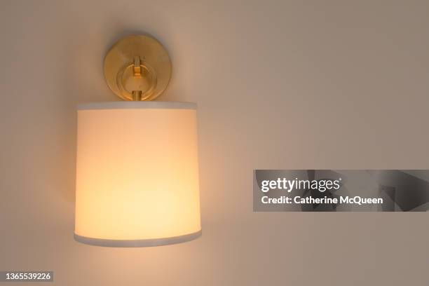 illuminated brass wall sconce in bright room - sconce stock pictures, royalty-free photos & images