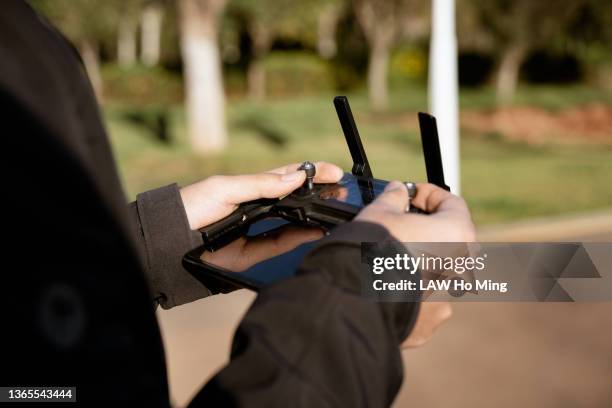 a pair of hands holding a drone's remote control - drone pilot stock pictures, royalty-free photos & images